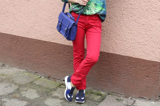 Woman in red jeans leaning against wall
